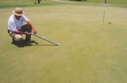 Ft. Lauderdale Country Club, Ft. Lauderdale, FL.  Mile Bailey, Superintendent testing Stimp Meter with height of cut gauge on green.