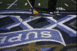 This is the field logo for SuperBowl XXXIX at Alltel Stadium, Jacksonville, Florida being hand raked to stand the grass up for a second painting.